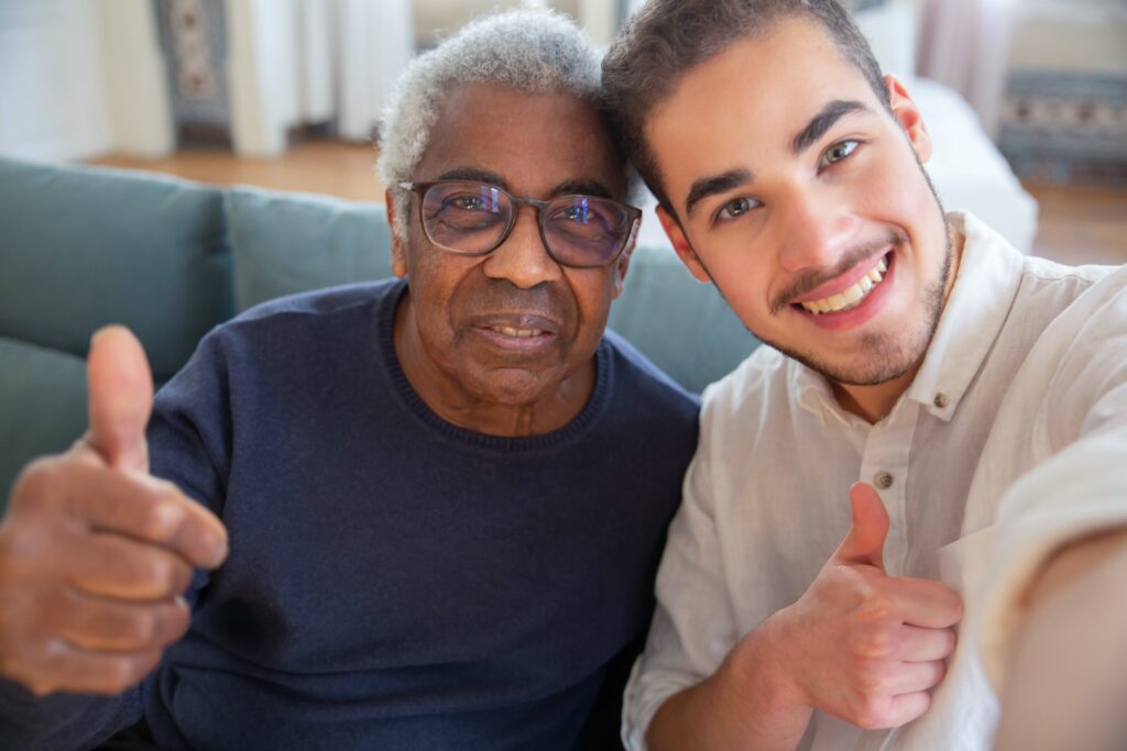 Image of 2 men looking at the camera smiling with their thumbs up